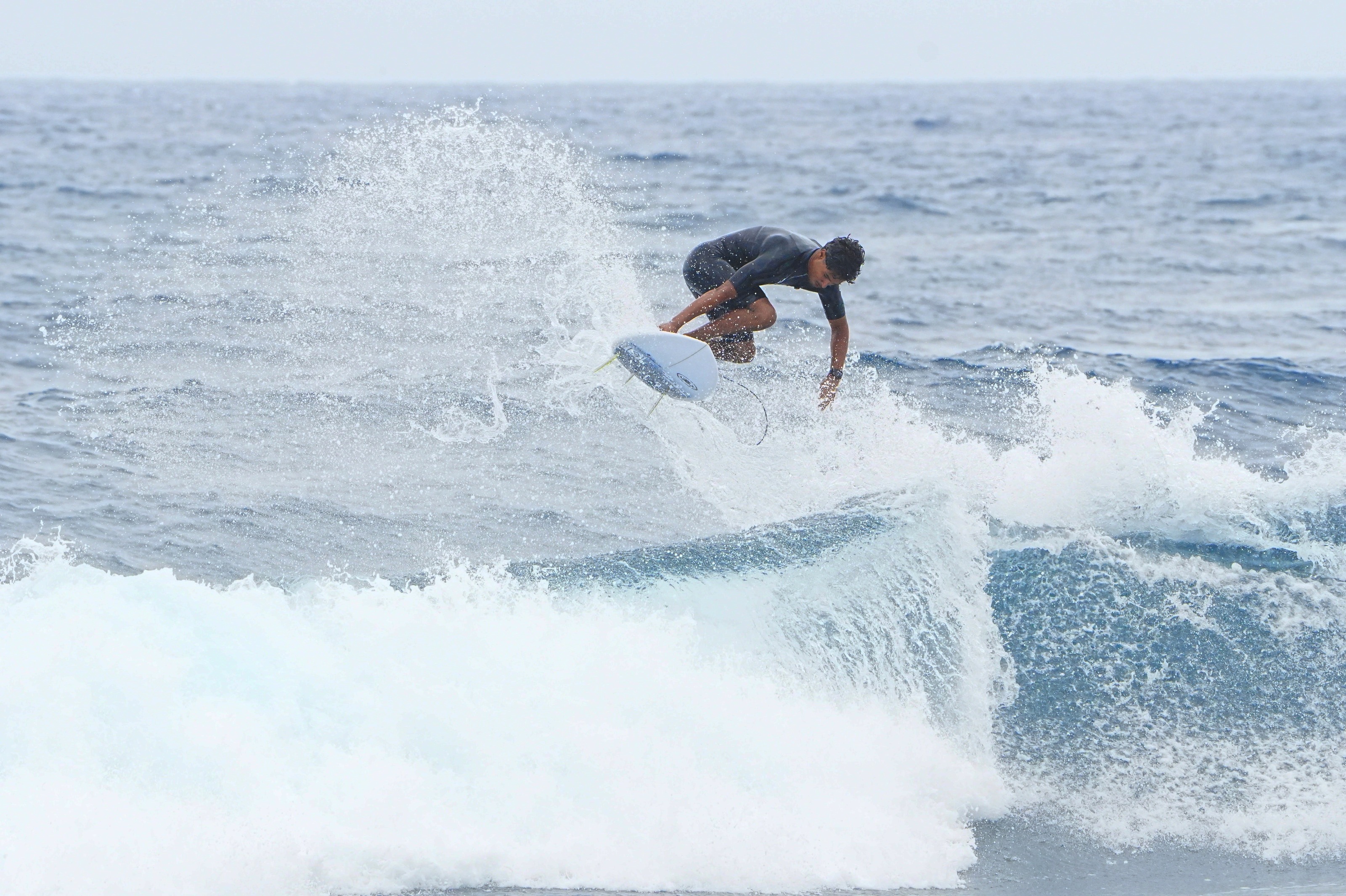 Surfista a rasgar a onda com muito spray