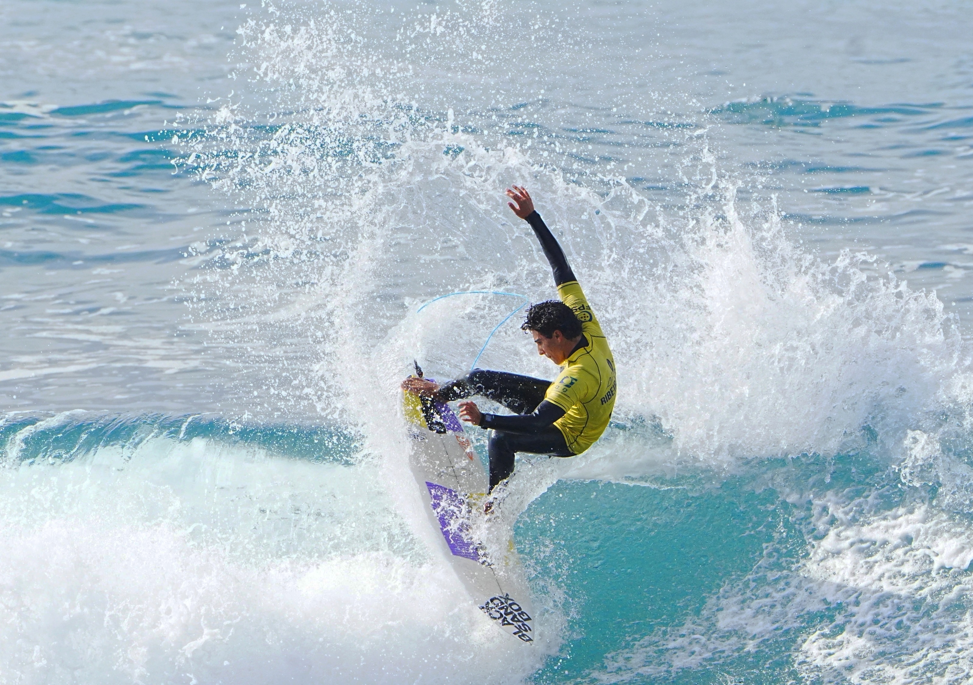 Surfista de lycra amarela a atacar o lip, envolto em spray